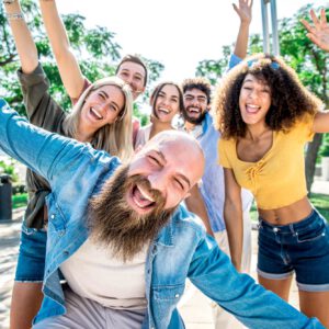 Big group of happy friends stands on city street with raised arms together